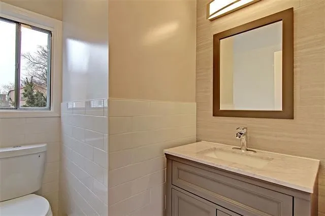 a bathroom with a granite countertop sink a toilet and a mirror
