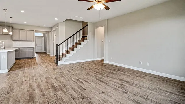 a view of staircase and kitchen with sink wooden floor and a chandelier
