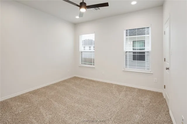 an empty room with windows and fan