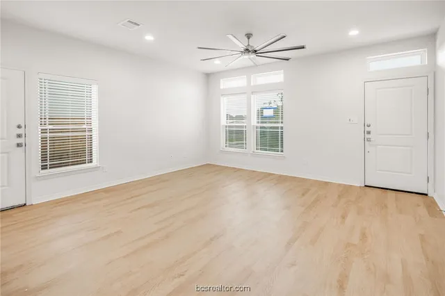 a view of an empty room with a window and wooden floor