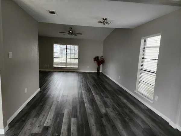 a view of empty room with wooden floor and fan