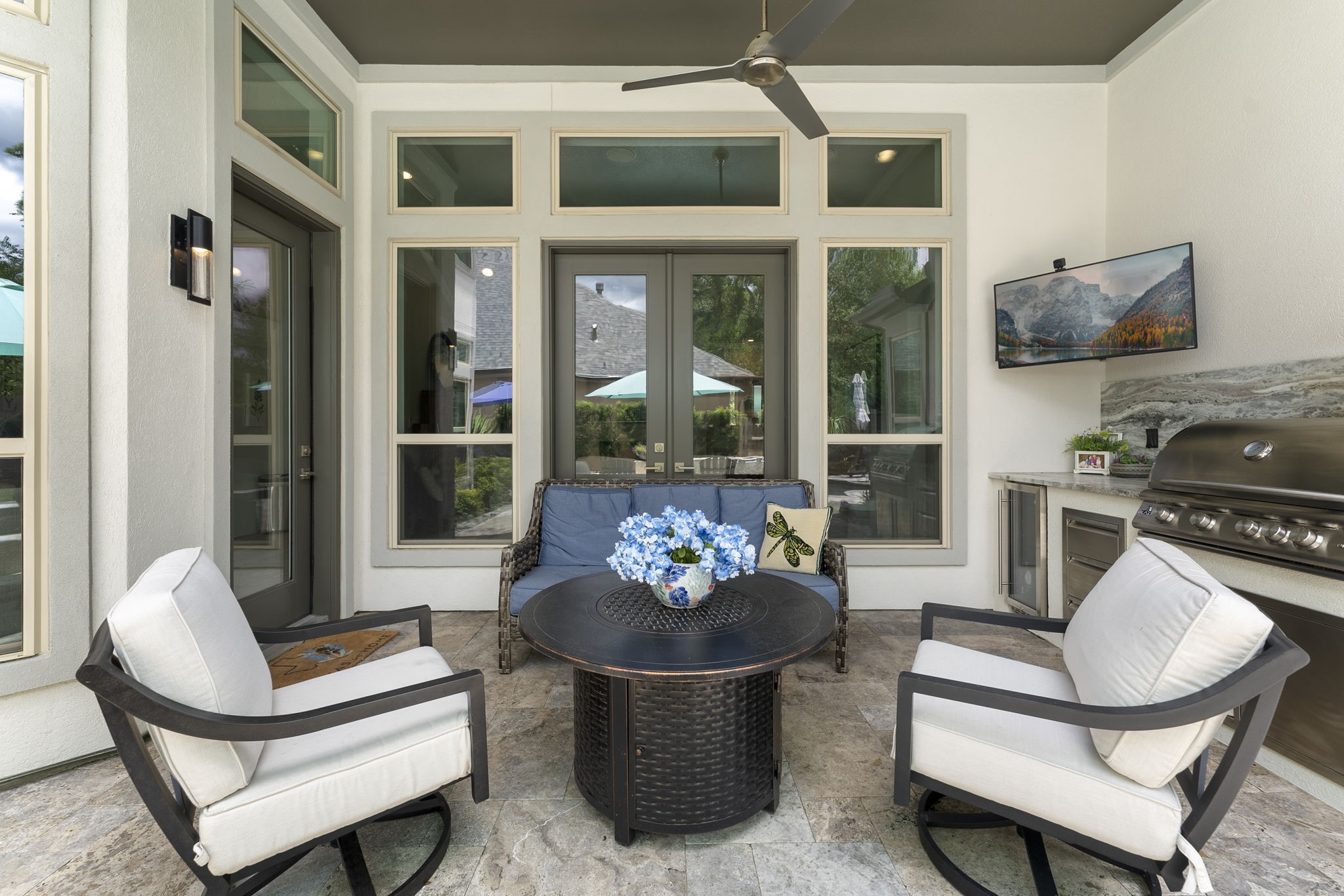 25607 Muirfield Bend Court Spring, TX 77389 - Photo 27 of 30 Covered outdoor living area featuring a built-in summer kitchen, beverage refrigerator, mounted television, and comfortable lounge seating—creating the perfect extension of the home for year-round entertaining and relaxing poolside.