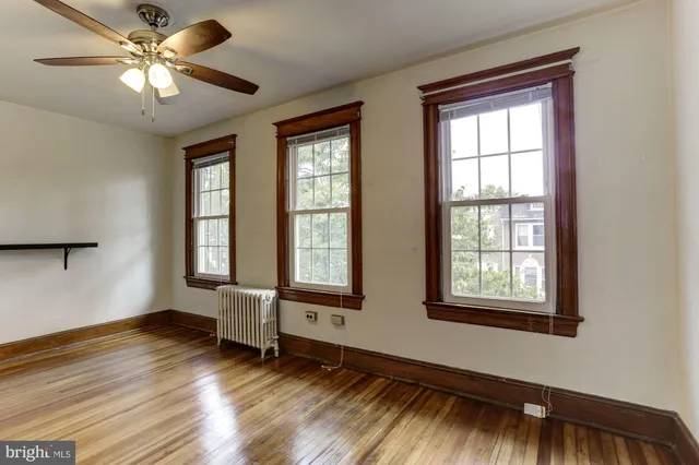an empty room with windows and fan