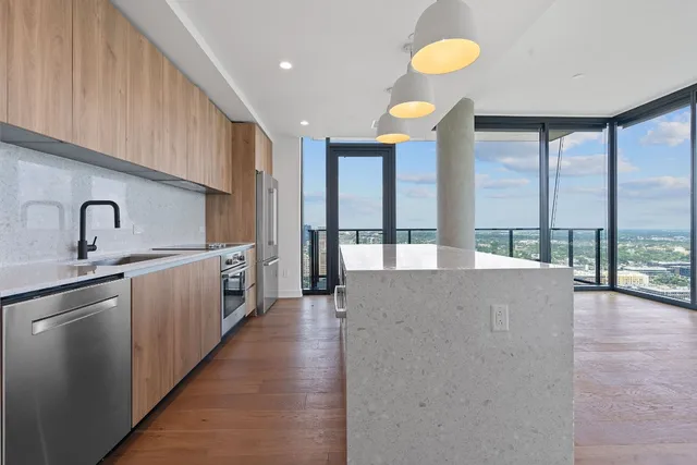 a view of a kitchen with kitchen island a large window a sink and cabinets