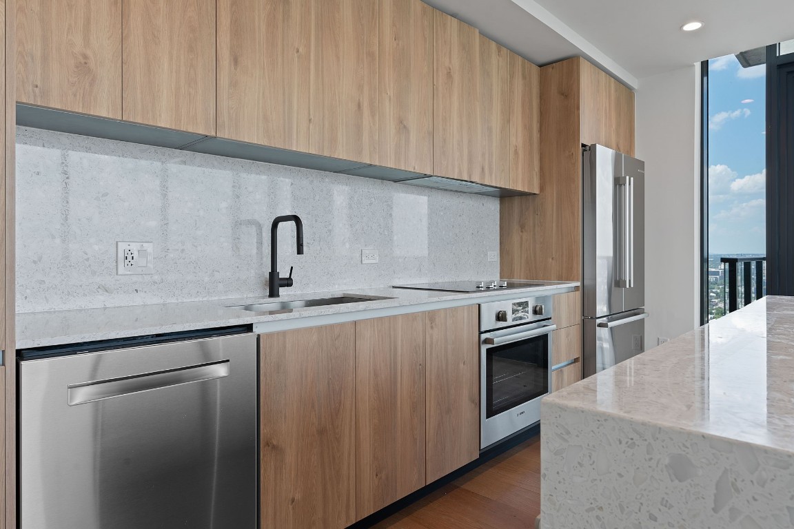 84 East Avenue, Unit 3404 Austin, TX 78701 - Photo 10 of 40 a kitchen with stainless steel appliances granite countertop a sink a stove and a refrigerator