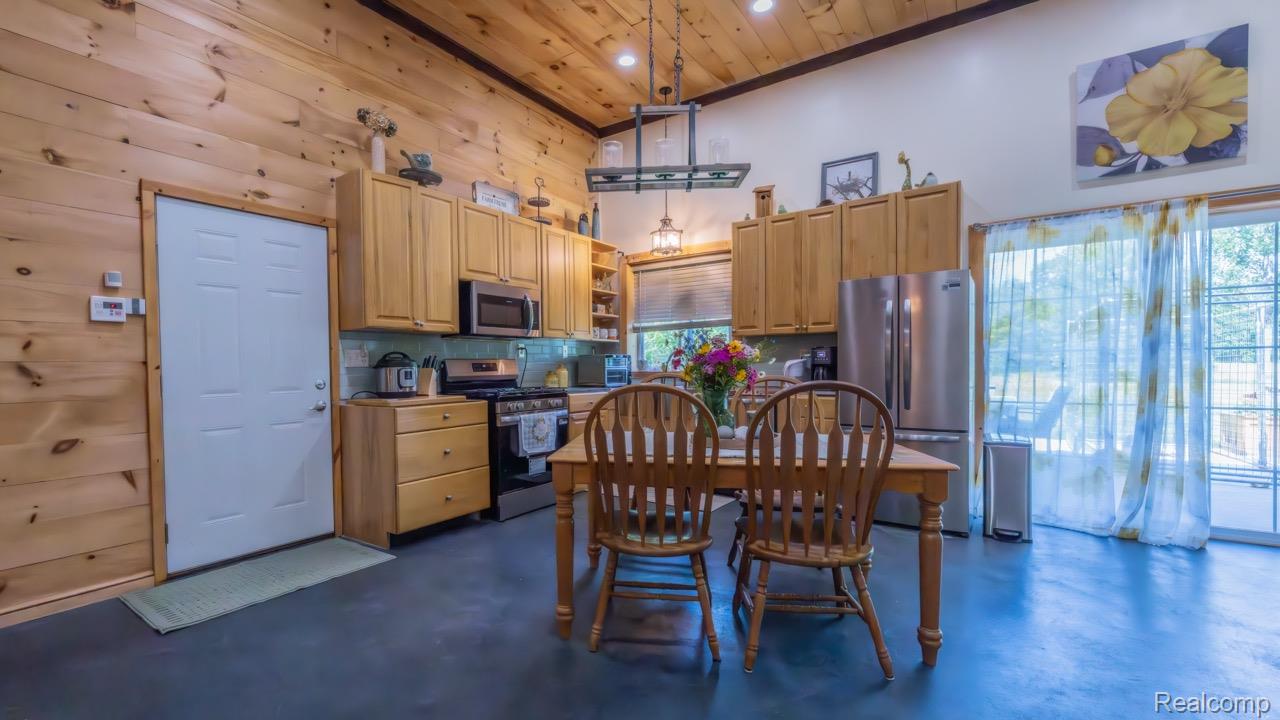 2418 South 41st Road South Cadillac, MI 49601 - Photo 14 of 57 Vaulted wood-paneled ceiling kitchen featuring wood cabinetry, stainless steel appliances, a tiled backsplash, and a sliding glass door