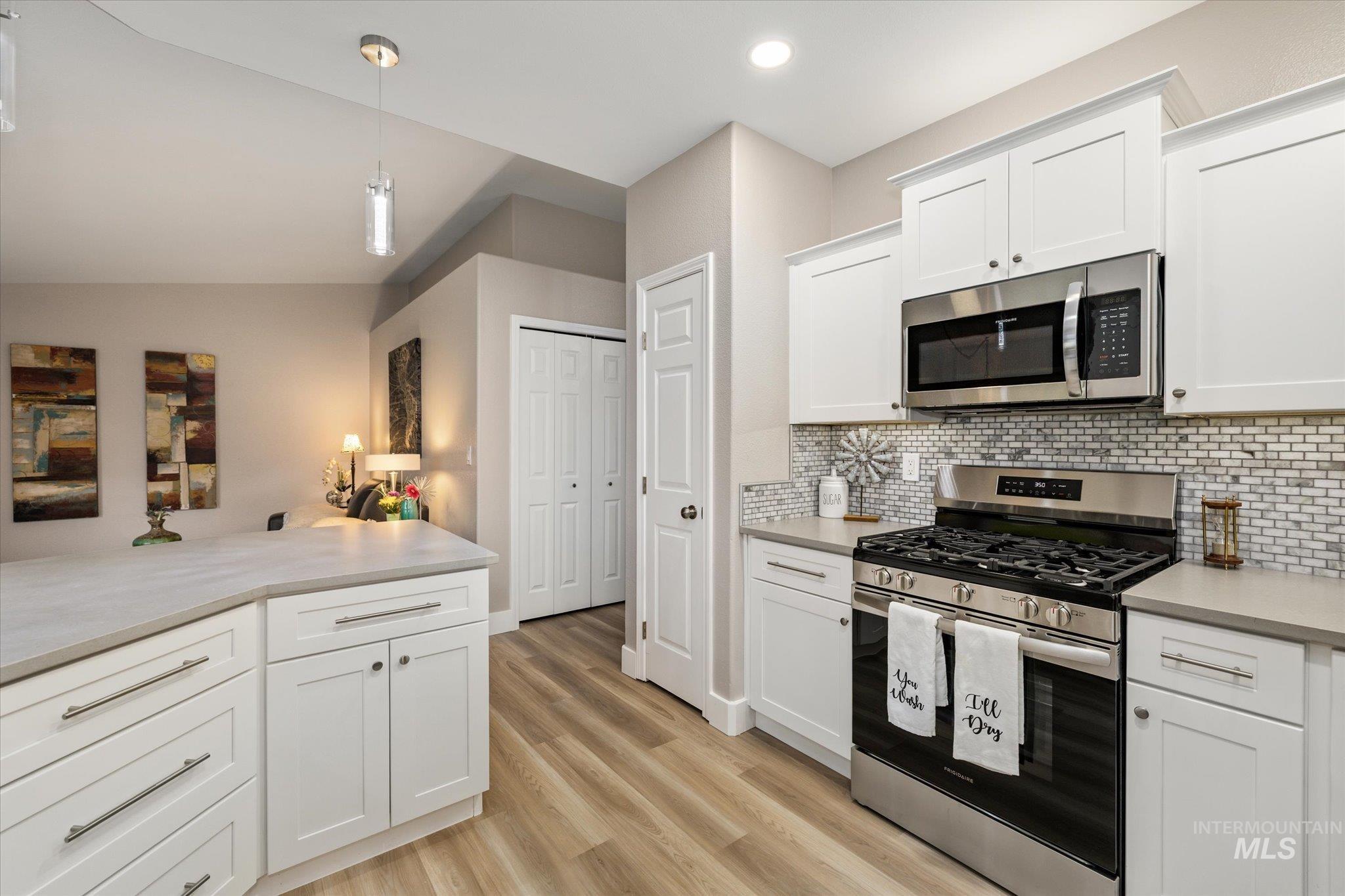 2250 North Amethyst Avenue Meridian, ID 83646 - Photo 15 of 50 Kitchen featuring stainless steel appliances, white cabinets, light countertops, light wood-style flooring, and hanging light fixtures
