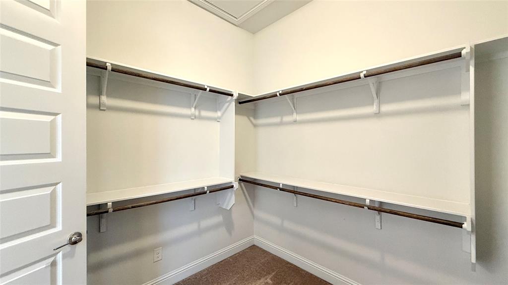 601 C-Bar Ranch Trail, Unit 27 Cedar Park, TX 78613 - Photo 26 of 29 Spacious walk-in closet featuring white built-in shelving, multiple hanging rods, warm neutral wall paint, and brown carpet flooring