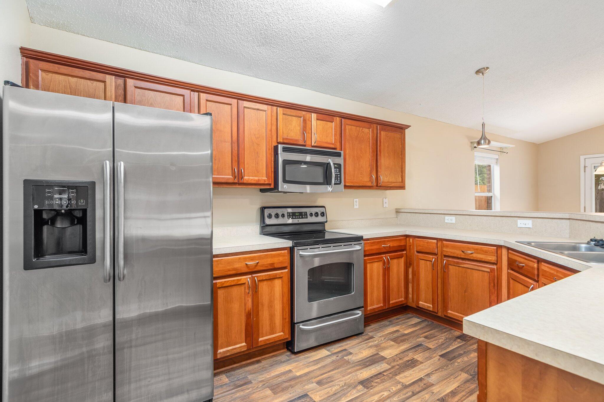 273 Limestone Circle Crestview, FL 32539 - Photo 12 of 36 a kitchen with stainless steel appliances granite countertop a refrigerator a stove and a sink with wooden floor