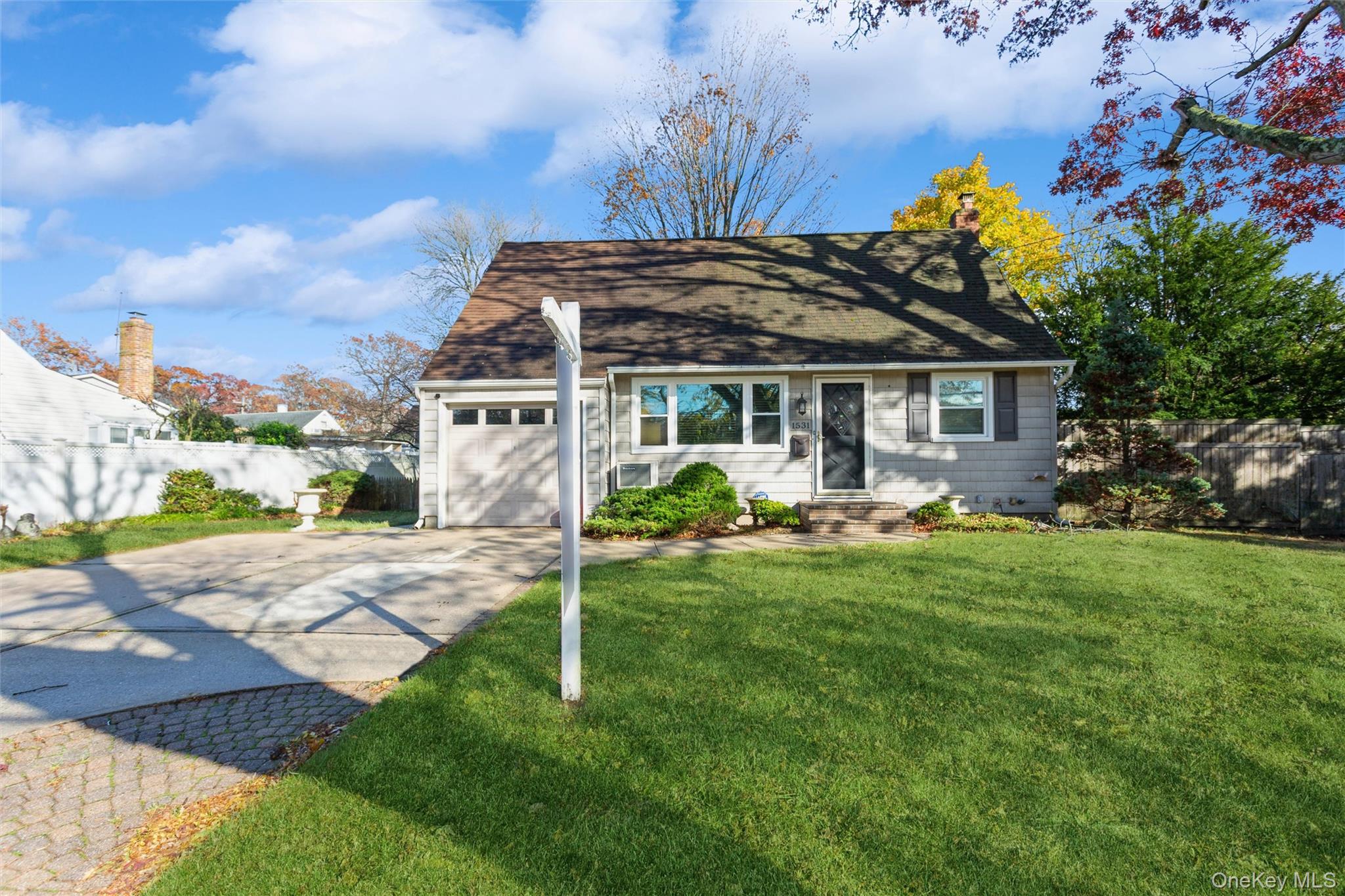 Cape cod house featuring driveway, a shingled roof, and an attached garage