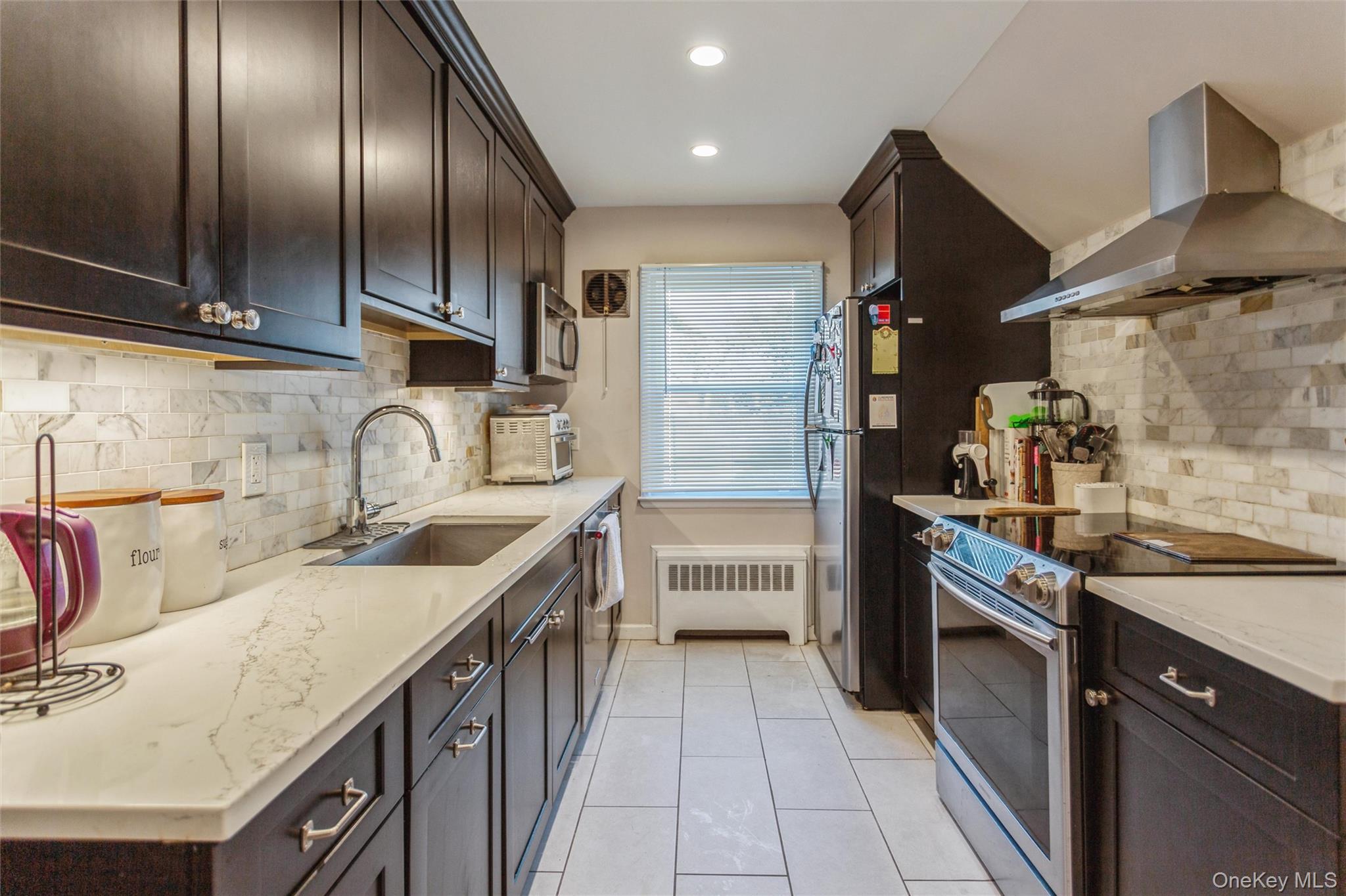 1531 Merrick Avenue Merrick, NY 11566 - Photo 12 of 26 Kitchen featuring backsplash, stainless steel appliances, ventilation hood, dark brown cabinetry, and recessed lighting