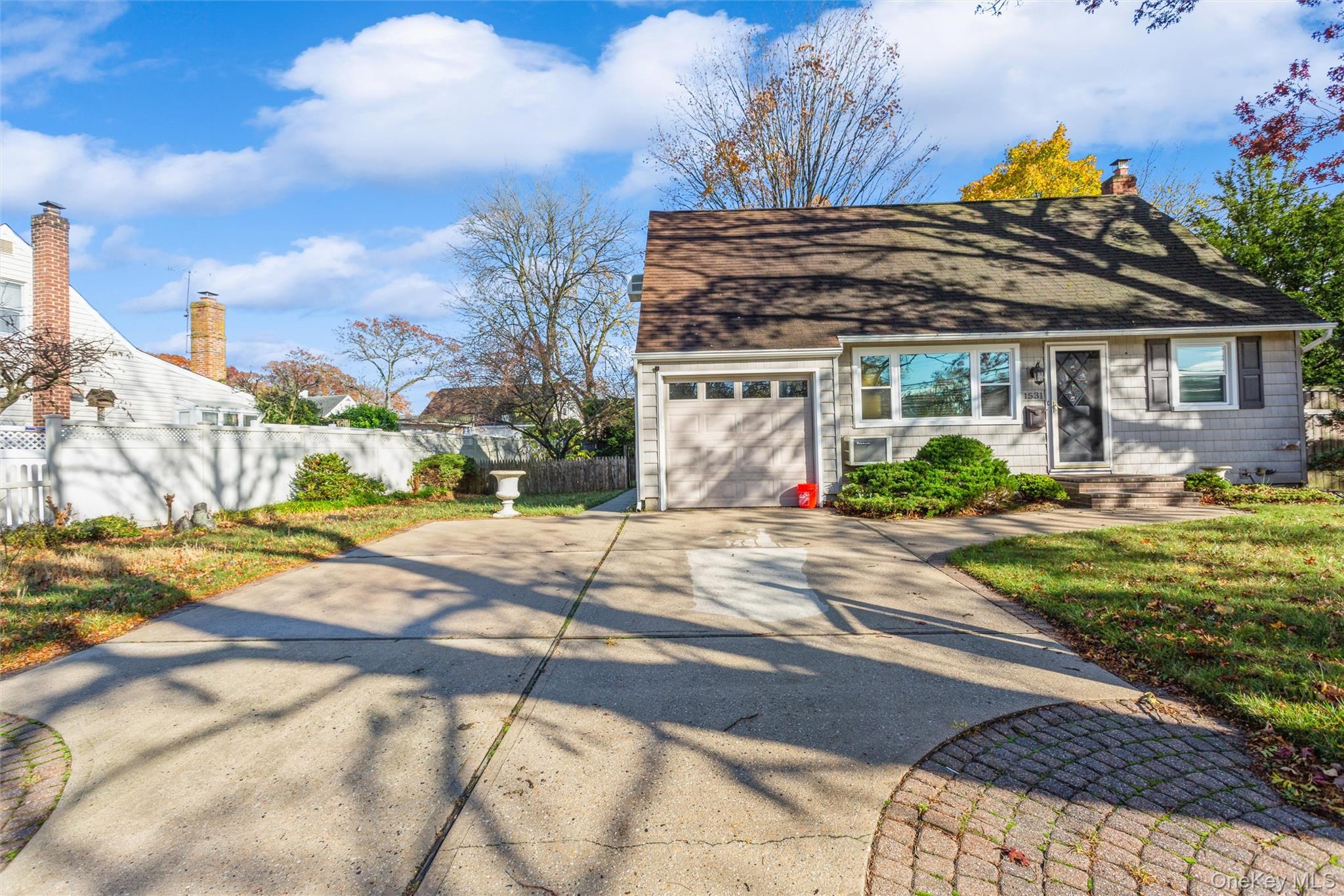 1531 Merrick Avenue Merrick, NY 11566 - Photo 2 of 26 View of front of home featuring concrete driveway, a shingled roof, and a chimney