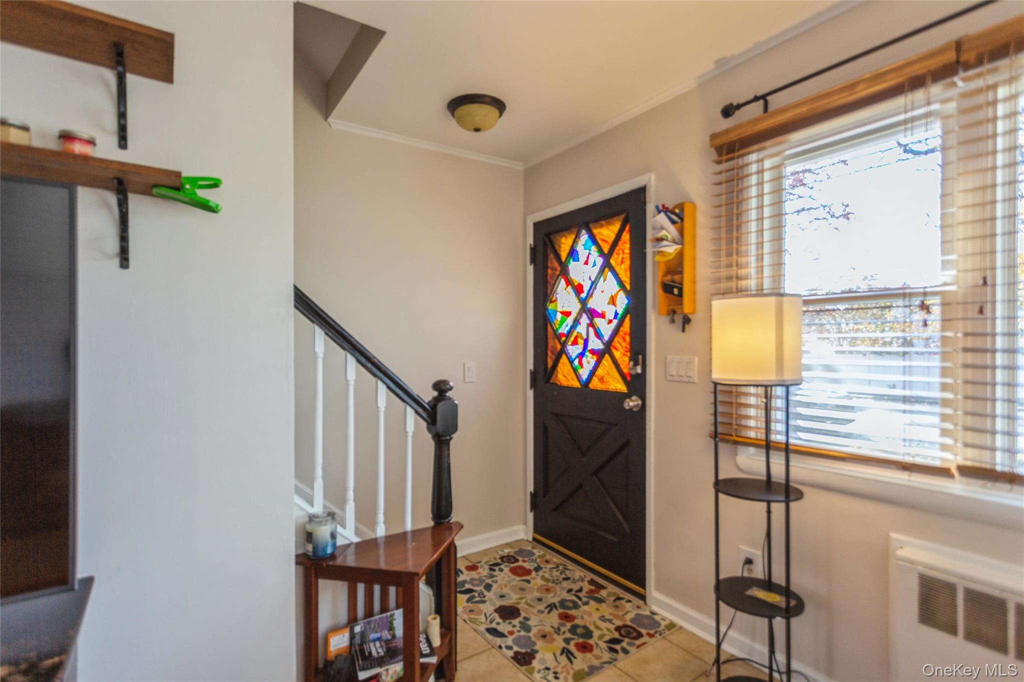 1531 Merrick Avenue Merrick, NY 11566 - Photo 5 of 26 Foyer with radiator heating unit, light tile patterned floors, stairway, and ornamental molding