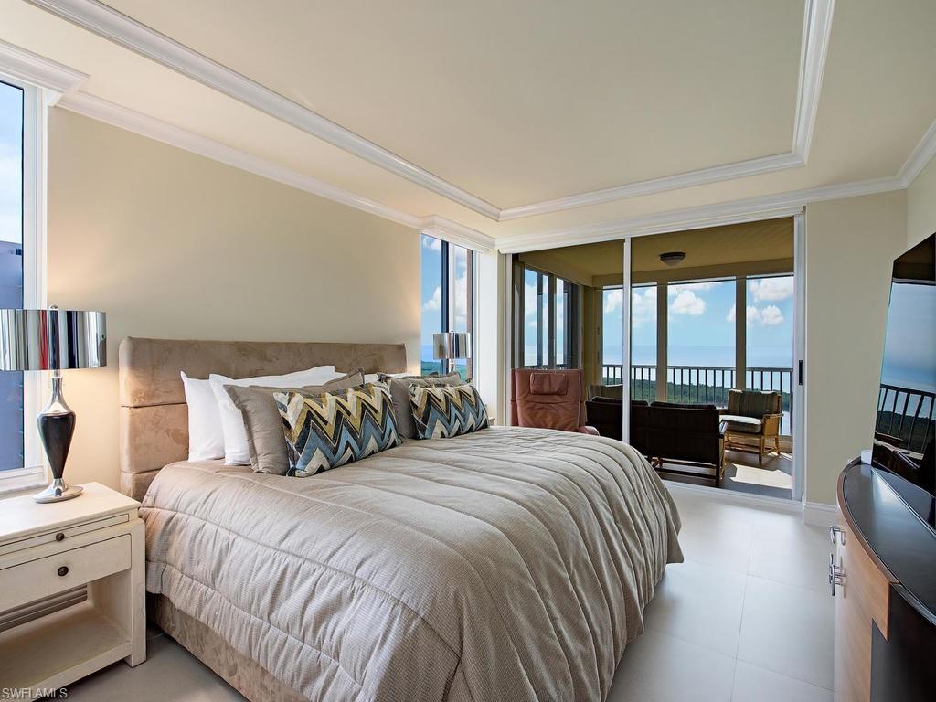 6849 Grenadier Boulevard, Unit 2104 Naples, FL 34108 - Photo 6 of 13 a bedroom with a bed and large windows
