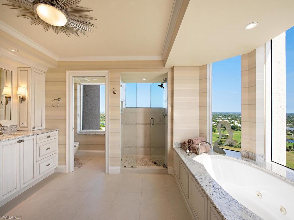 6849 Grenadier Boulevard, Unit 2104 Naples, FL 34108 - Photo 8 of 13 a spacious bathroom with a granite countertop tub sink and mirror