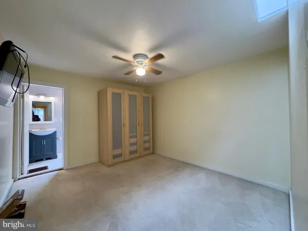 an empty room with chandelier fan and windows