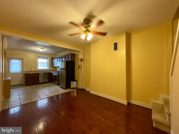 a view of an empty room with wooden floor and a ceiling fan