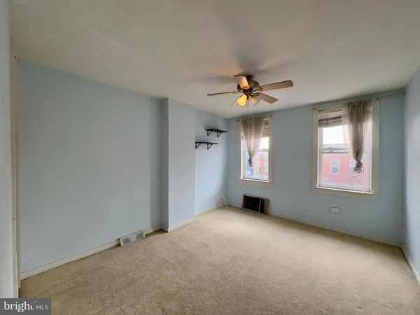 an empty room with windows and fan