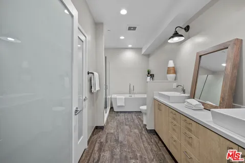 a bathroom with a granite countertop double vanity sink a mirror and a shower