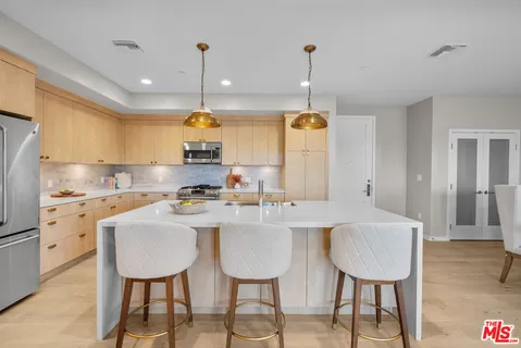 a kitchen with stainless steel appliances granite countertop a sink a stove a refrigerator cabinets dining table and chairs