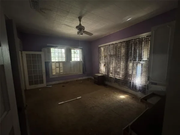 en empty room with windows and ceiling fan