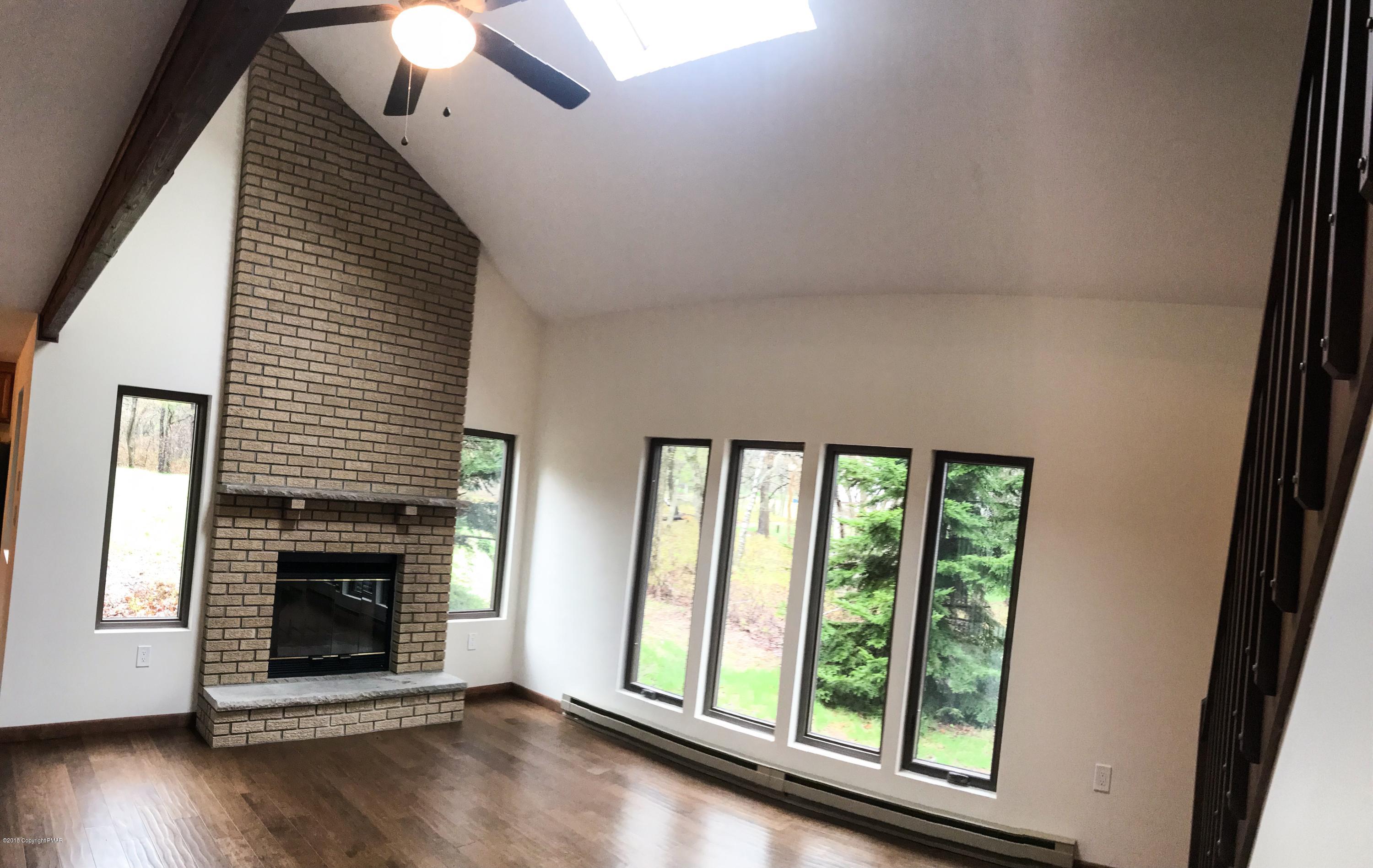 219 Ryan Road Blakeslee, PA 18610 - Photo 5 of 16 an empty room with wooden floor fireplace and windows