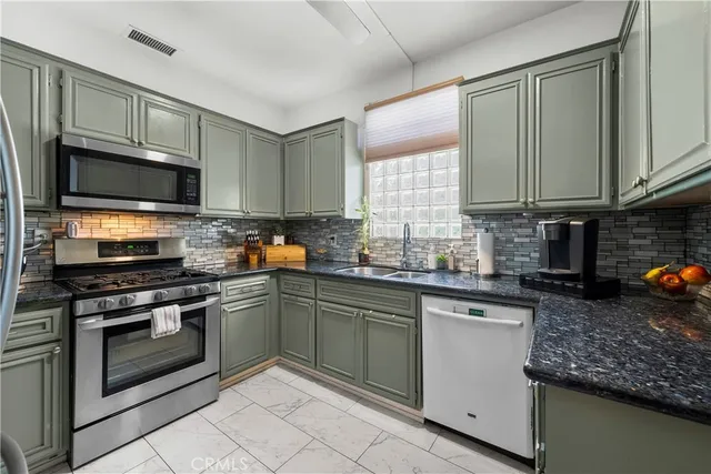 a kitchen with stainless steel appliances granite countertop a sink stove microwave and refrigerator