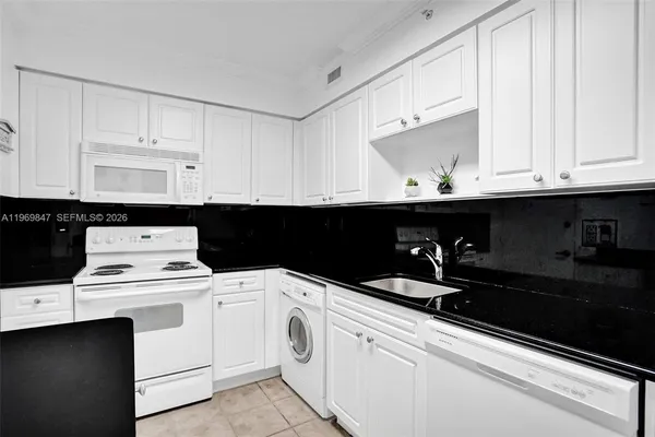 a kitchen with white cabinets and sink