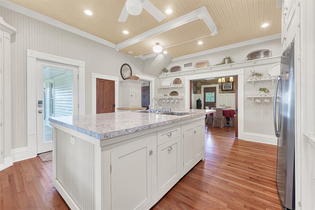 1425 Lone Star Road Celina, TX 75009 - Photo 5 of 40 The expansive island with double sinks anchors a 2022 kitchen remodel featuring updated countertops, oven, refrigerator, and dishwasher, all thoughtfully integrated into the home's Victorian character. Whether baking with grandchildren or serving a crowd during the holidays, this kitchen was made to bring people together.