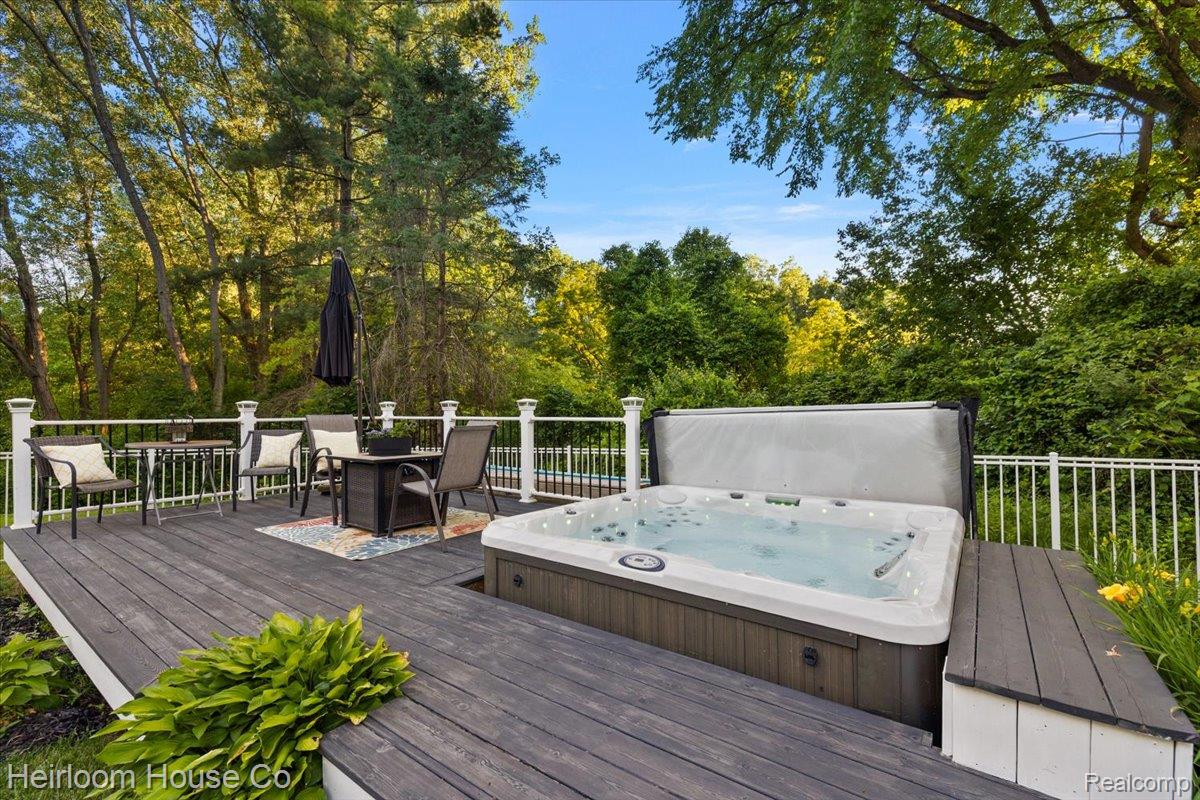 49001 Hanford Road Canton, MI 48187 - Photo 8 of 98 Expansive composite deck featuring a built-in hot tub, white railing, and ample space for outdoor furnishings, surrounded by mature trees