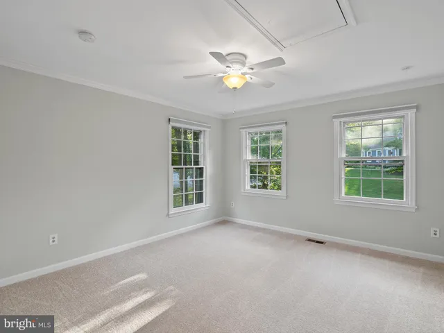 a view of an empty room with wooden floor and window