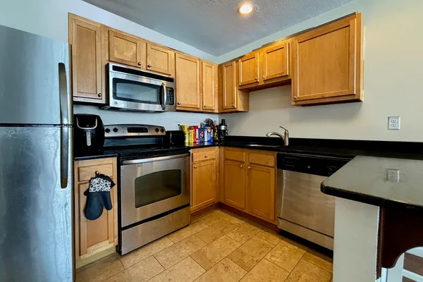 a kitchen with stainless steel appliances granite countertop a stove a sink dishwasher and a microwave oven with cabinets