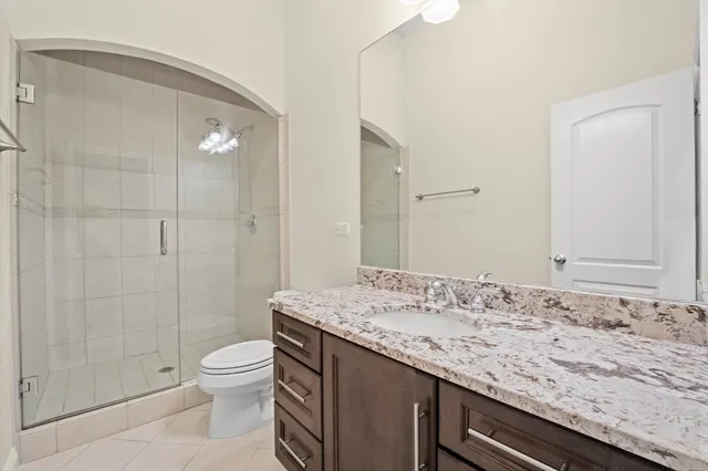 a bathroom with a granite countertop sink a toilet and shower