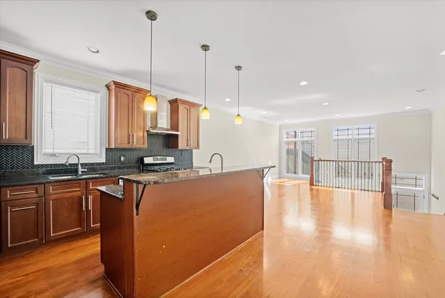 a kitchen with stainless steel appliances granite countertop a sink a stove and a wooden floors