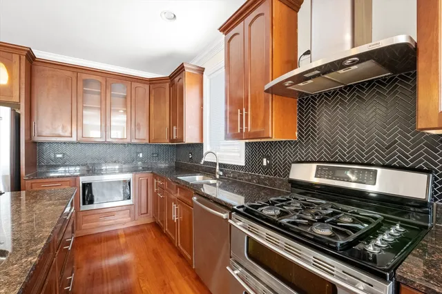 a kitchen with stainless steel appliances granite countertop a stove a sink and a microwave