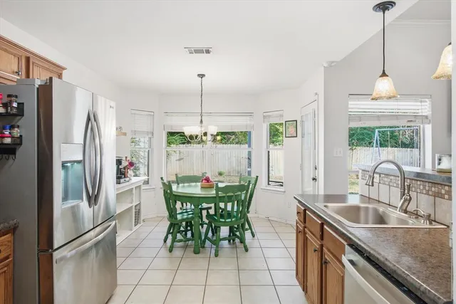 a kitchen with stainless steel appliances granite countertop a refrigerator a sink a stove and a dining table