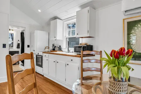a white kitchen with stainless steel appliances granite countertop a white cabinets a sink and a potted plant