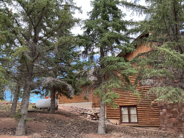 550 State Line Road Manila, UT 84046 - Photo 39 of 41 Log-sided exterior with a natural wood finish, featuring a stone foundation accent and mature evergreen trees