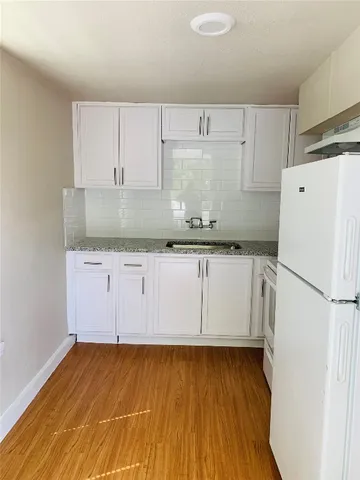 a kitchen with granite countertop white cabinets and refrigerator