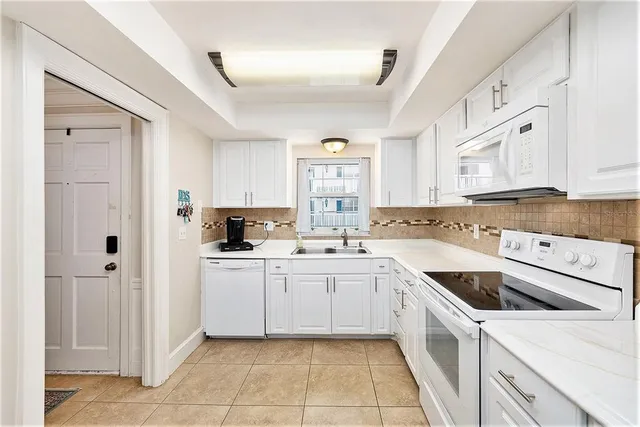 a kitchen with white cabinets and white appliances