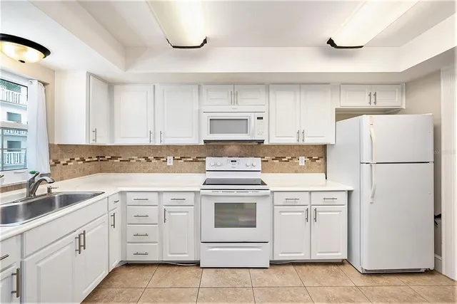 a kitchen with white cabinets and white appliances