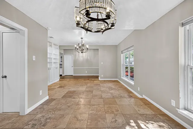 a view of a hallway with a chandelier fan and windows