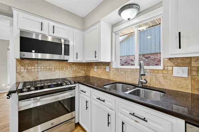 a kitchen with granite countertop a sink stove and microwave