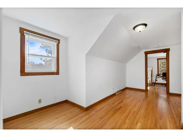 a view of an empty room and window with wooden floor