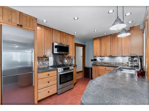 a kitchen with granite countertop wooden cabinets a dining table and chairs