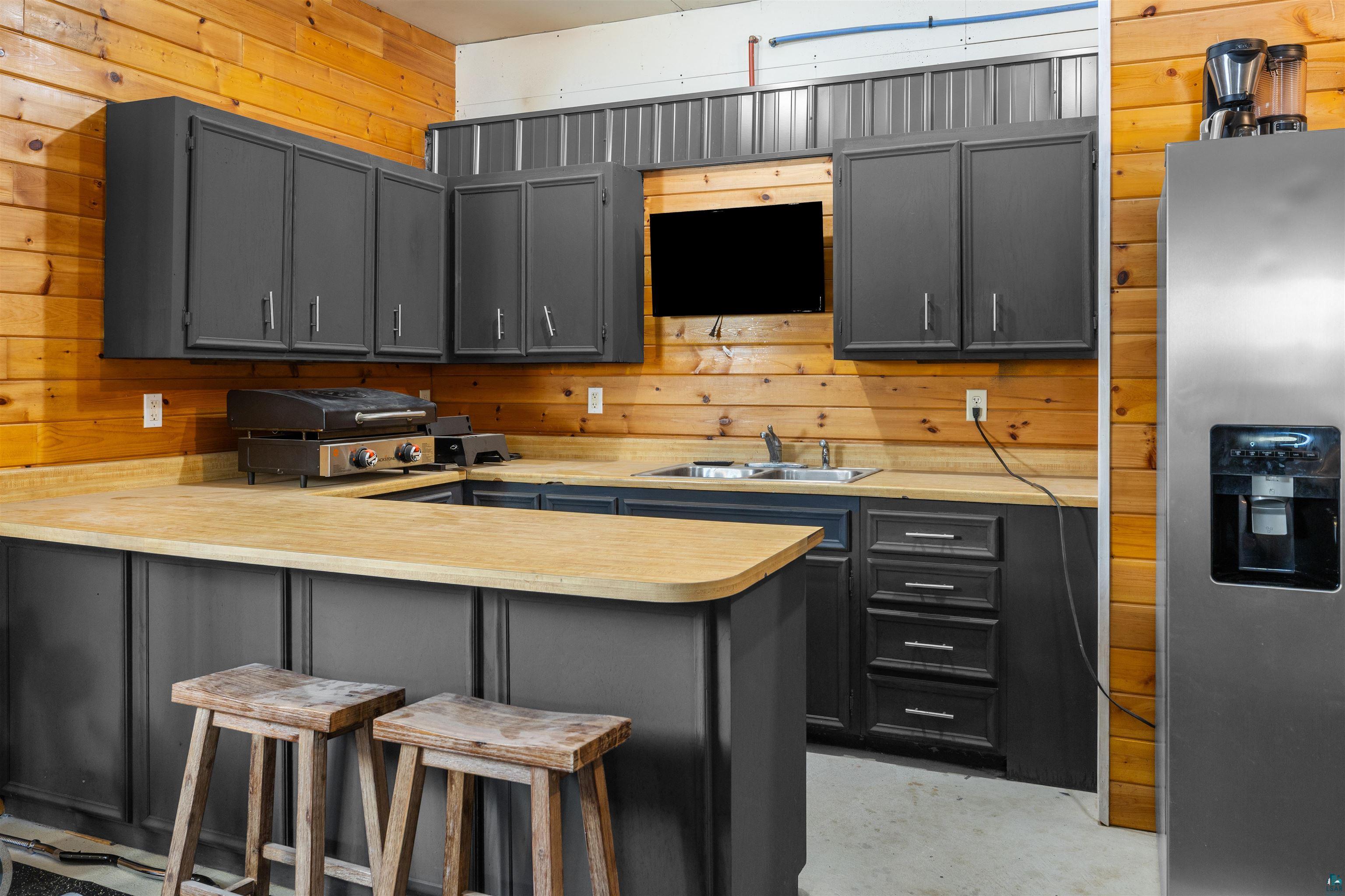 13462 Villa Road Ely, MN 55731 - Photo 26 of 68 Garage kitchen featuring a peninsula, a kitchen breakfast bar, gray cabinets, light countertops, and wooden walls