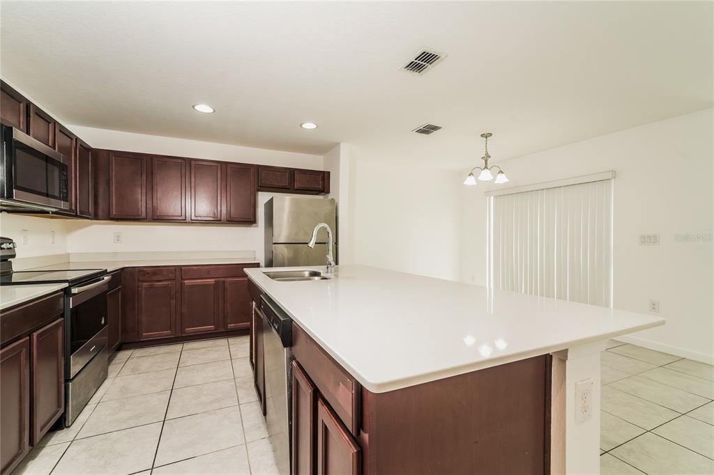 1473 Lucerne Loop Road Northeast Winter Haven, FL 33881 - Photo 9 of 25 a kitchen with a sink a stove a refrigerator and cabinets