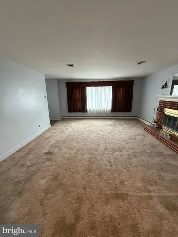 a view of an empty room with window and a kitchen