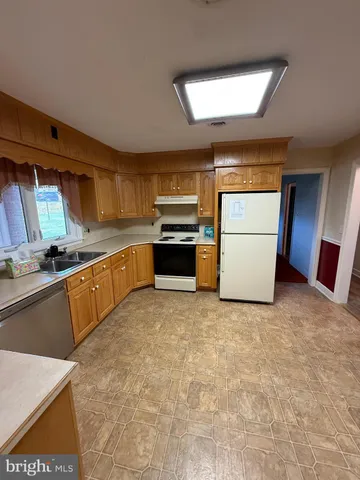 a kitchen with granite countertop a refrigerator a stove top oven a sink and dishwasher
