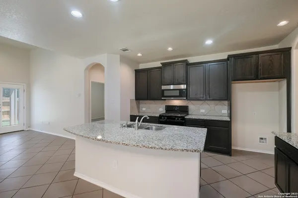 a kitchen with kitchen island granite countertop a sink a stove a refrigerator and a oven
